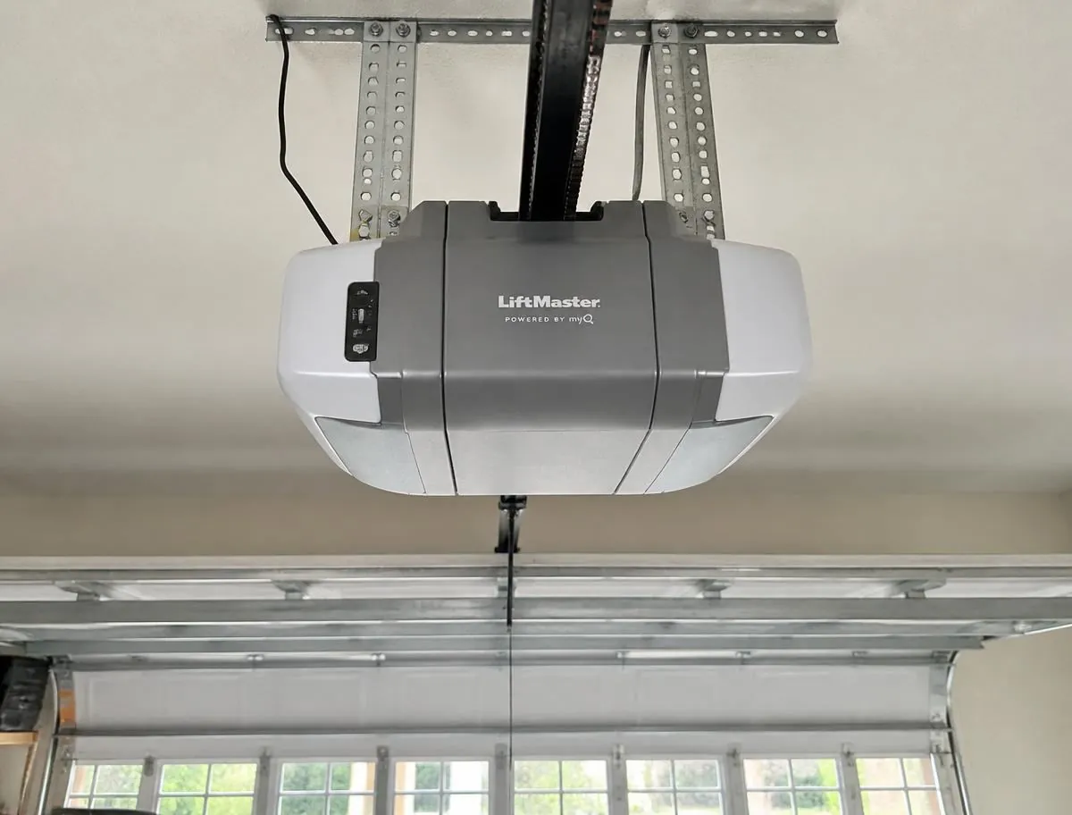 Technician servicing a LiftMaster garage door opener motor unit on the ceiling