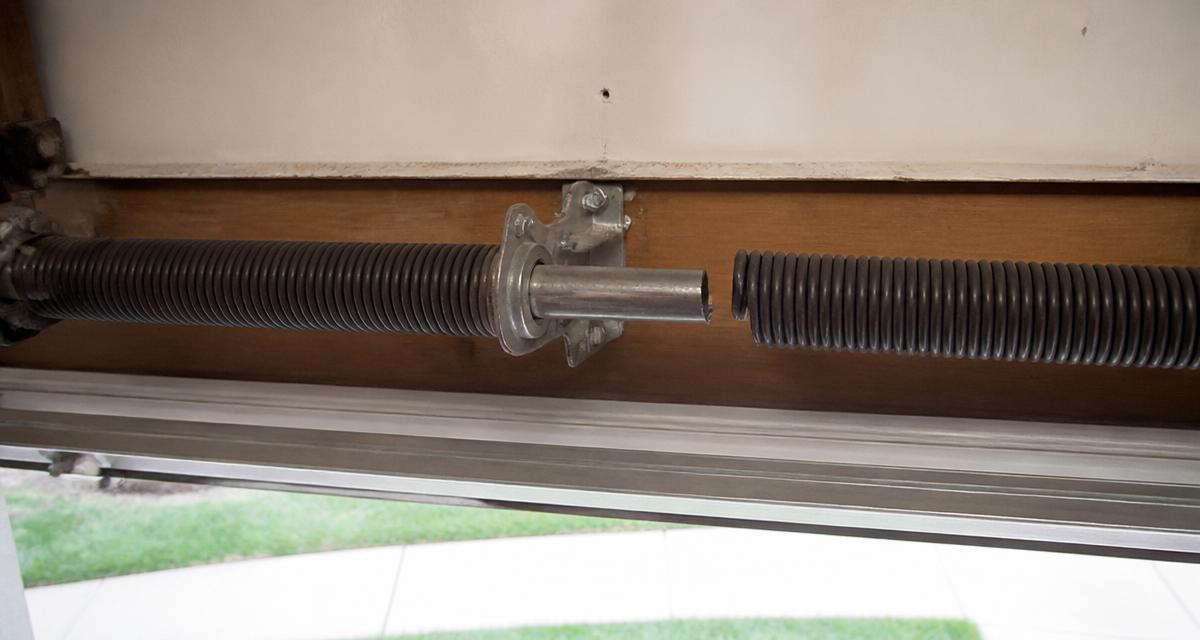 Broken garage door torsion spring on the shaft above a door showing the telltale gap in the coil